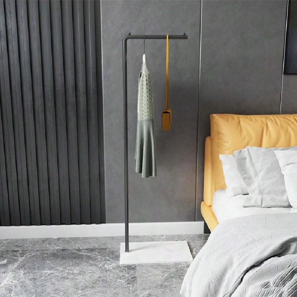 Slim black metal clothes rail with white base in a grey bedroom
