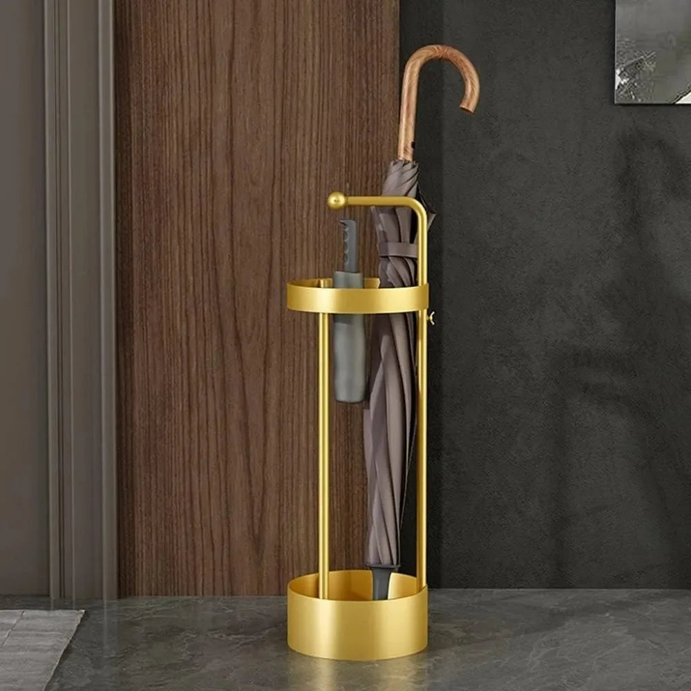 Slim gold metal umbrella stand holding an umbrella in a hallway